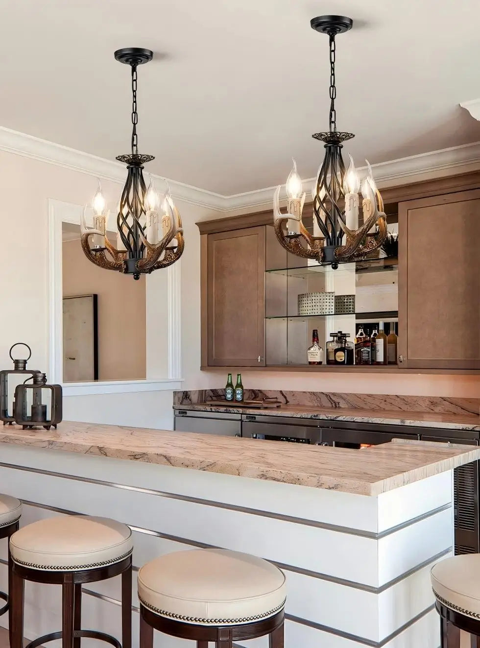 Two antler chandeliers hanging above a kitchen island with bar stools, enhancing a stylish rustic kitchen.
