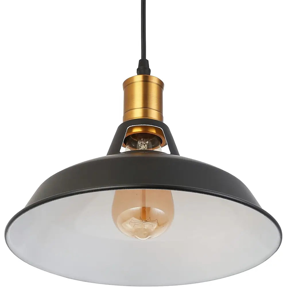 Angled view of a single black industrial farmhouse pendant light with a white interior, brass socket, and exposed vintage bulb, showing the warm light effect.