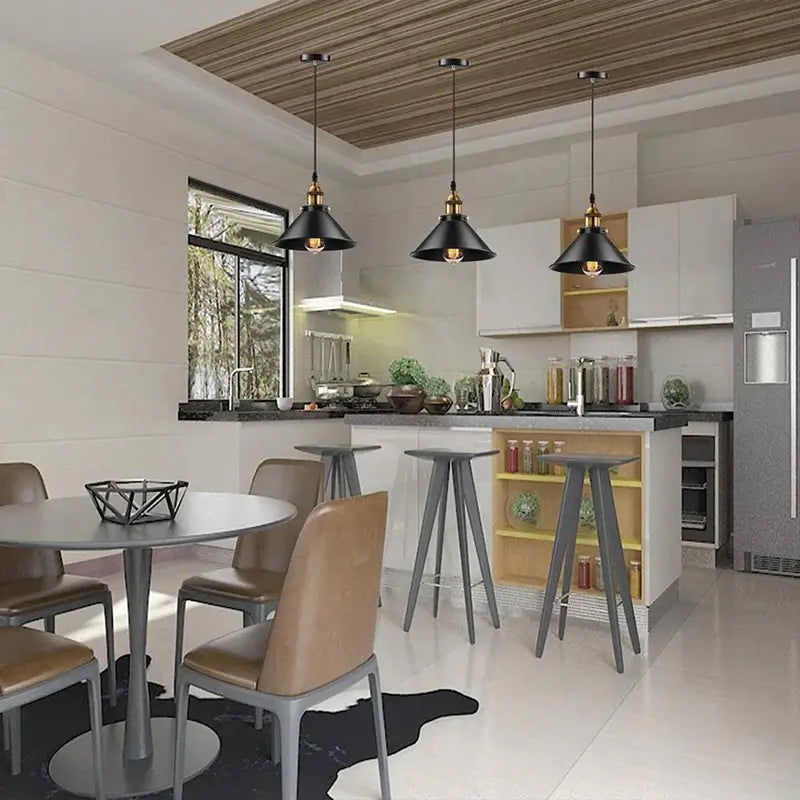 Three black pendant lights illuminating a modern kitchen island with bar stools and a dining area.