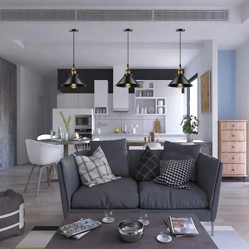 Three black industrial pendant lights installed above a modern living room and kitchen open concept space.