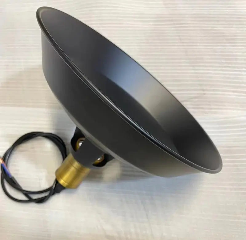 Underside view of the matte black metal dome shade and brass light fixture socket and wiring, showing quality construction.