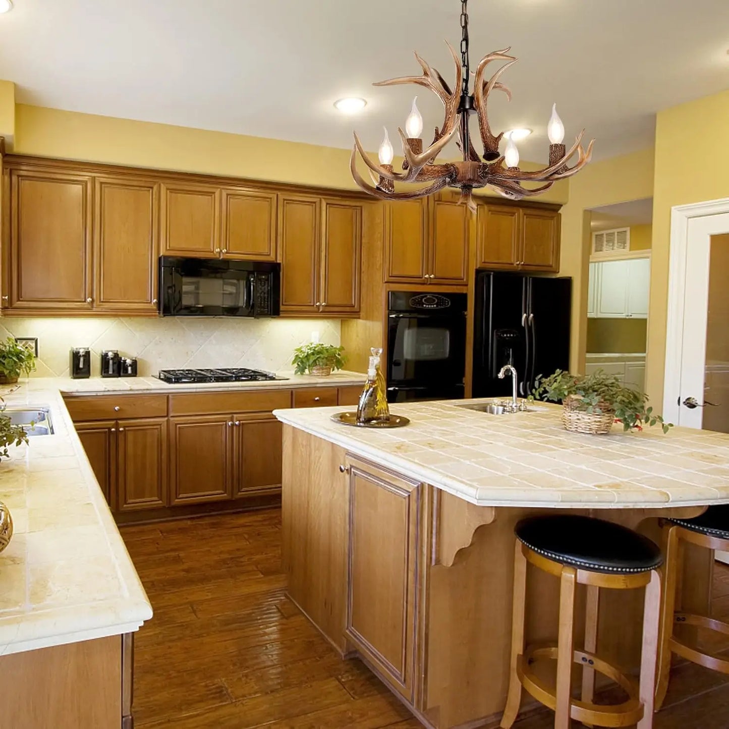 Single antler chandelier hanging above a kitchen island in a rustic-style kitchen, providing warm lighting and a unique aesthetic.