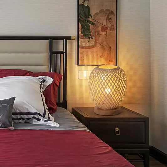 A handwoven bamboo table lamp placed on a bedside table, creating a warm and relaxing atmosphere in a modern bedroom.