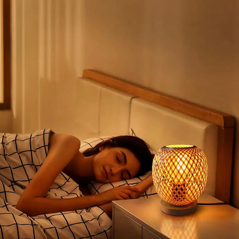 A bamboo table lamp glowing softly on a bedside table, providing cozy lighting for a restful night.