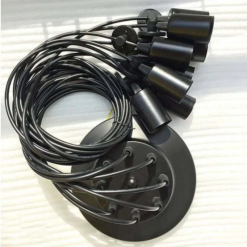 A black cable light fixture kit laid out, displaying the central black mounting plate, multiple black lamp holders, and coiled black electrical cables, representing the components of a DIY spider chandelier.