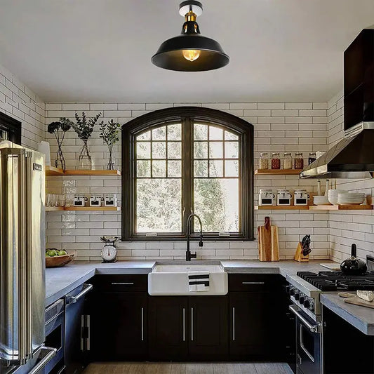 Industrial black ceiling light fixture installed in a kitchen with modern black and white decor.