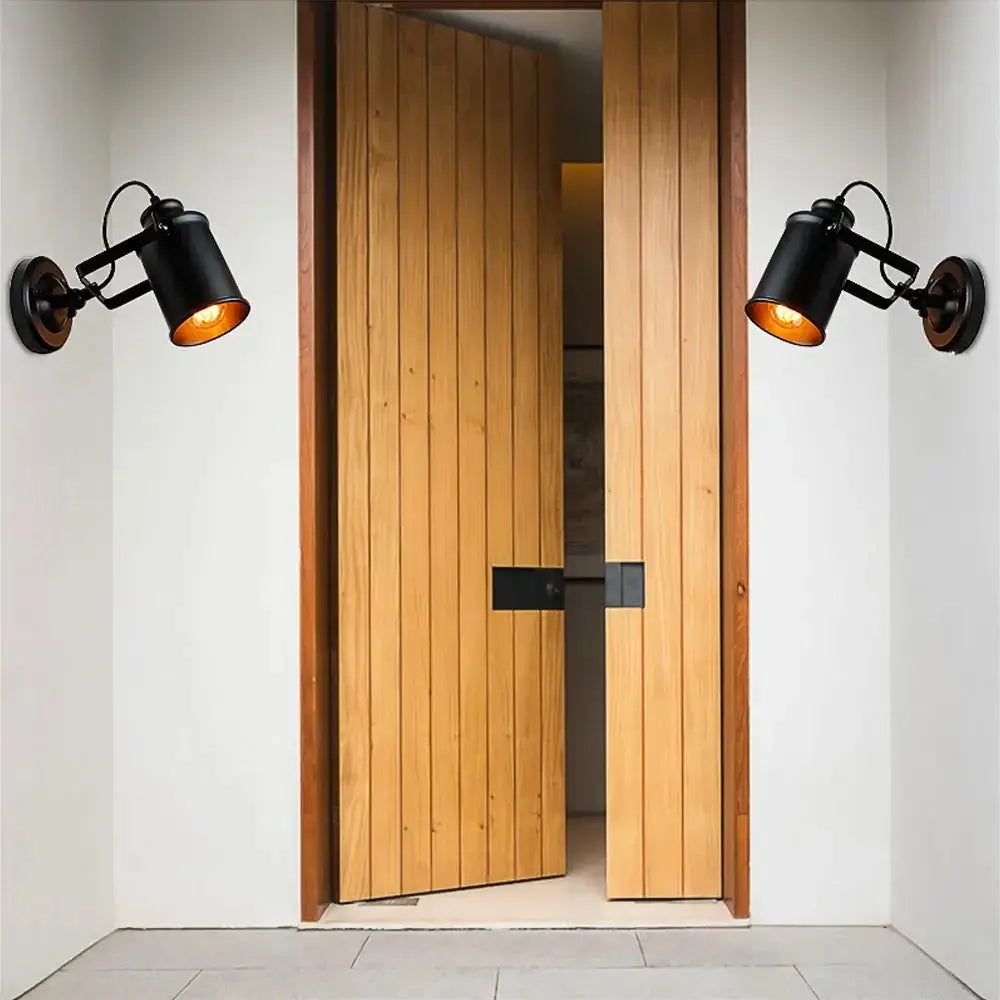 Pair of black metal wall sconces installed at an outdoor entryway, enhancing the doorway with warm vintage lighting.