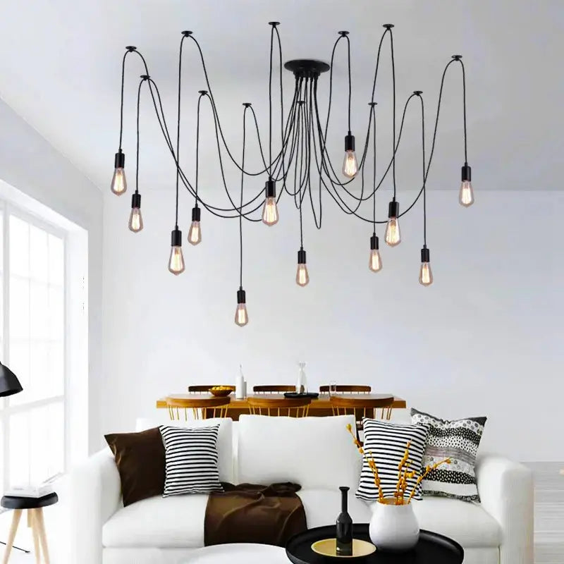 Black pendant lighting in a living room setting, showcasing a spider-style multi-bulb chandelier with long, draping black cables suspended above a white sofa and coffee table.