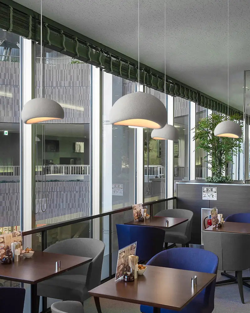 Pendant lighting in a modern cafe with natural tones and glass walls.