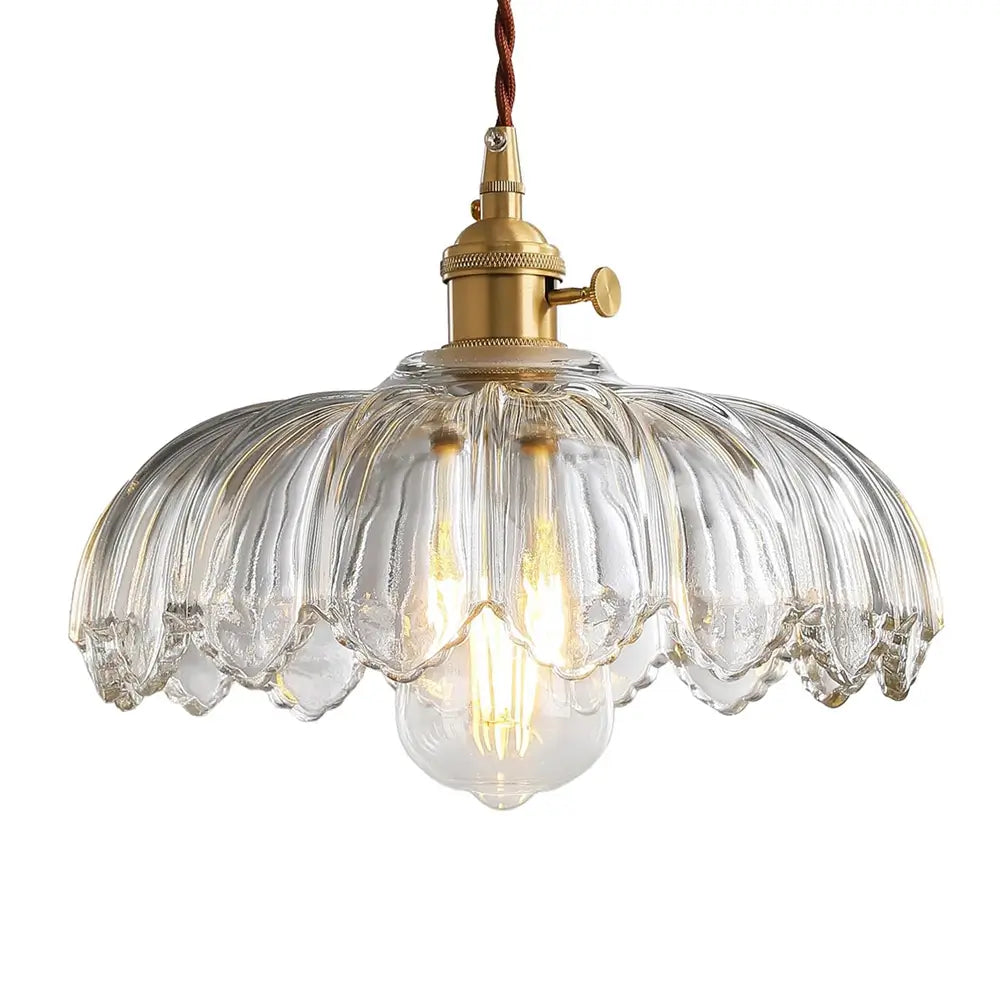A close-up of a clear fluted glass pendant light with a scalloped shade and vintage brass fixture, showing the detailed design.
