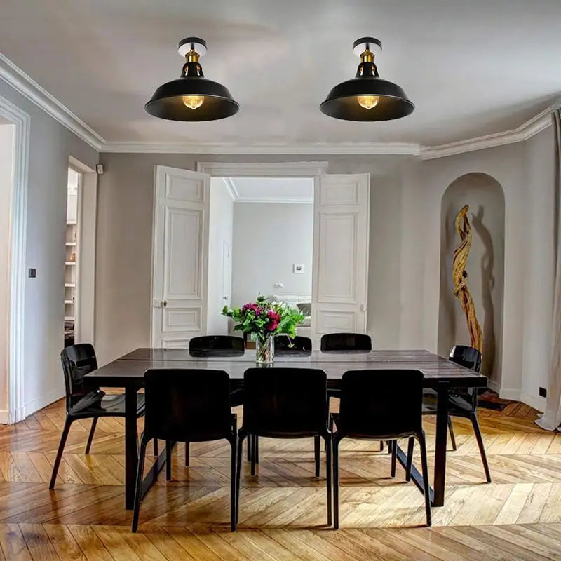Vintage black industrial ceiling lights illuminating a dining room with a rustic wooden table and modern chairs.