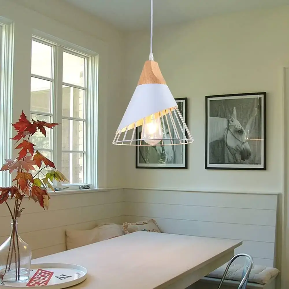 White metal cage pendant light installed above a rustic-style dining table in a farmhouse setting.