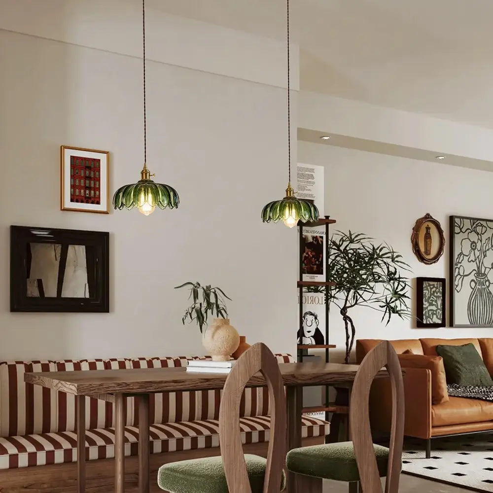 A green glass hanging lamp provides a warm and inviting light over a kitchen counter, enhancing the home's ambiance.