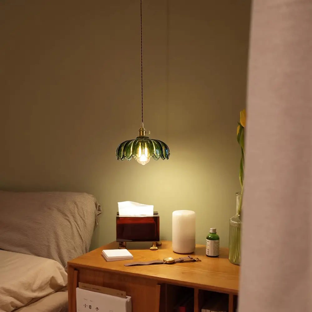 A green glass pendant light hanging in a living room, complementing the sofa and adding a pop of color to the decor.