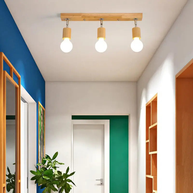 Ceiling-mounted wooden light fixture with three bulbs in a modern hallway