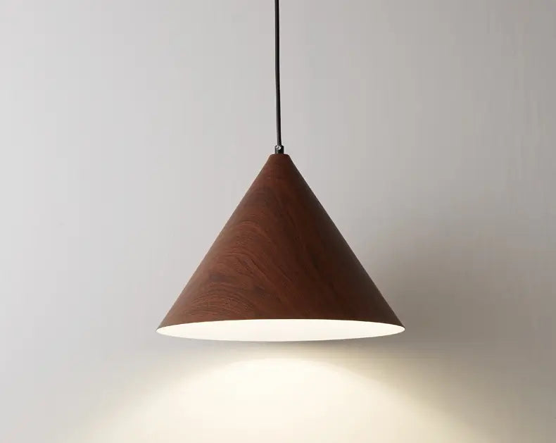 Iron cone pendant lamp with faux wood finish lit up against the wall.