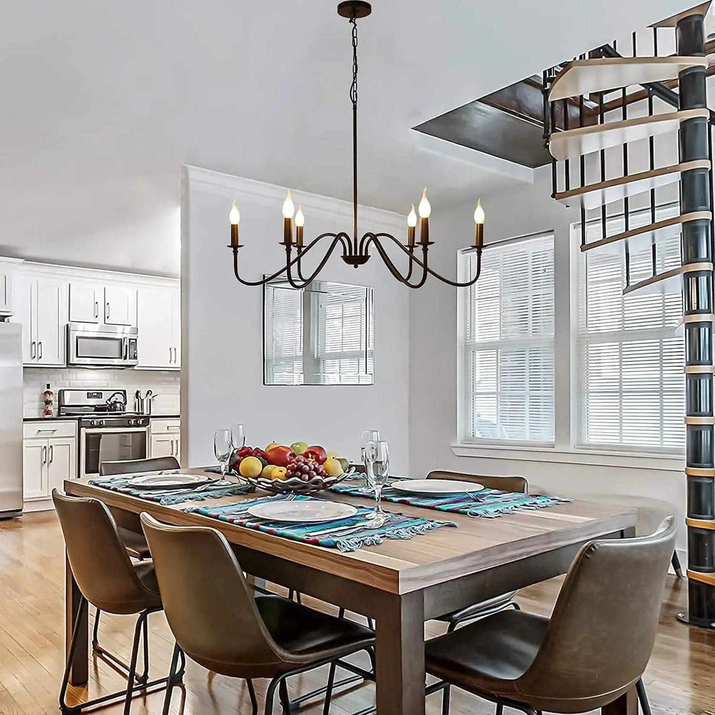 A black 6-light chandelier hanging over a wooden dining table in an open-concept kitchen and dining area.