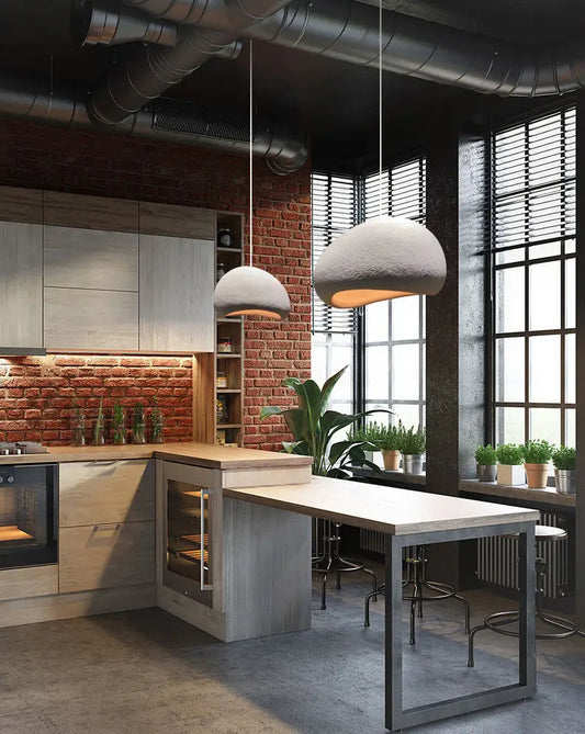 Industrial kitchen with exposed pipes and soft-white pendant lights over the counter.