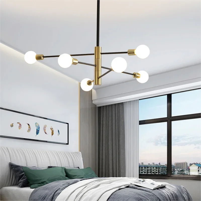 Modern minimalist chandelier with 6 lights in black and gold, hanging in a cozy bedroom with large windows and soft neutral decor.