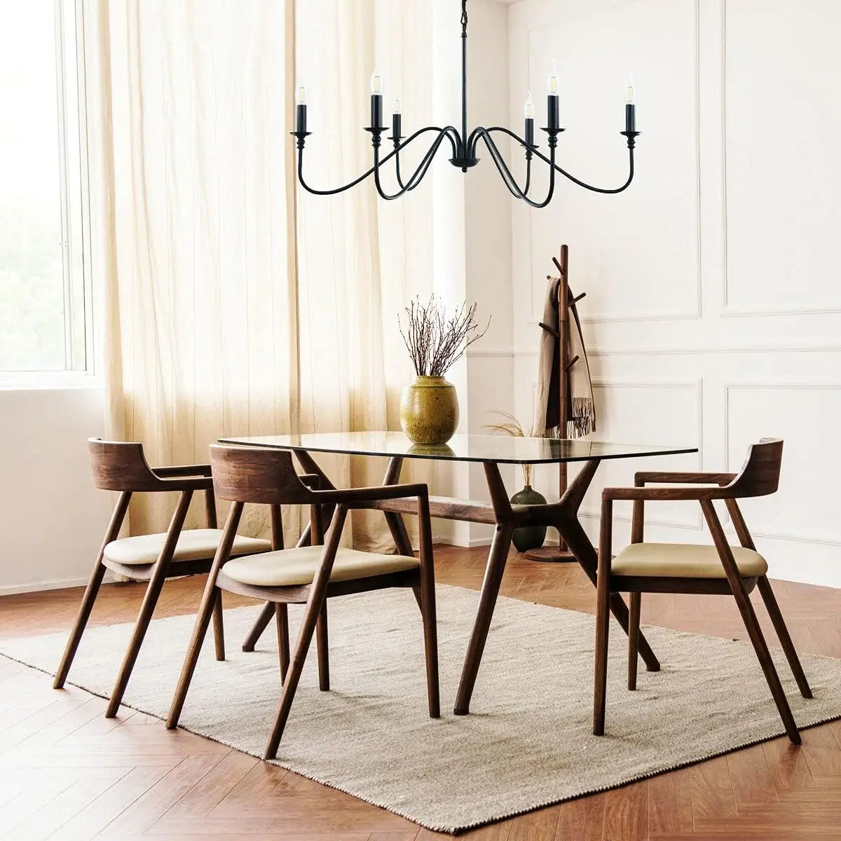 A black 6-light chandelier in a minimalist dining area featuring a glass table and modern wooden chairs.