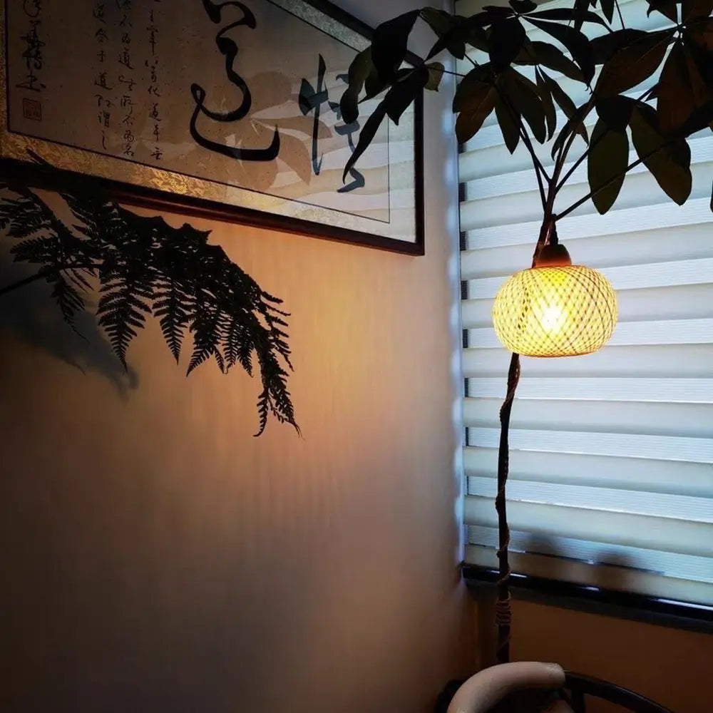 Minimalist pendant lamp with bamboo shade hanging near window with plants