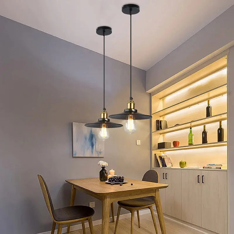 Two black industrial pendant lights illuminating a dining room table, perfect for modern farmhouse or industrial decor.