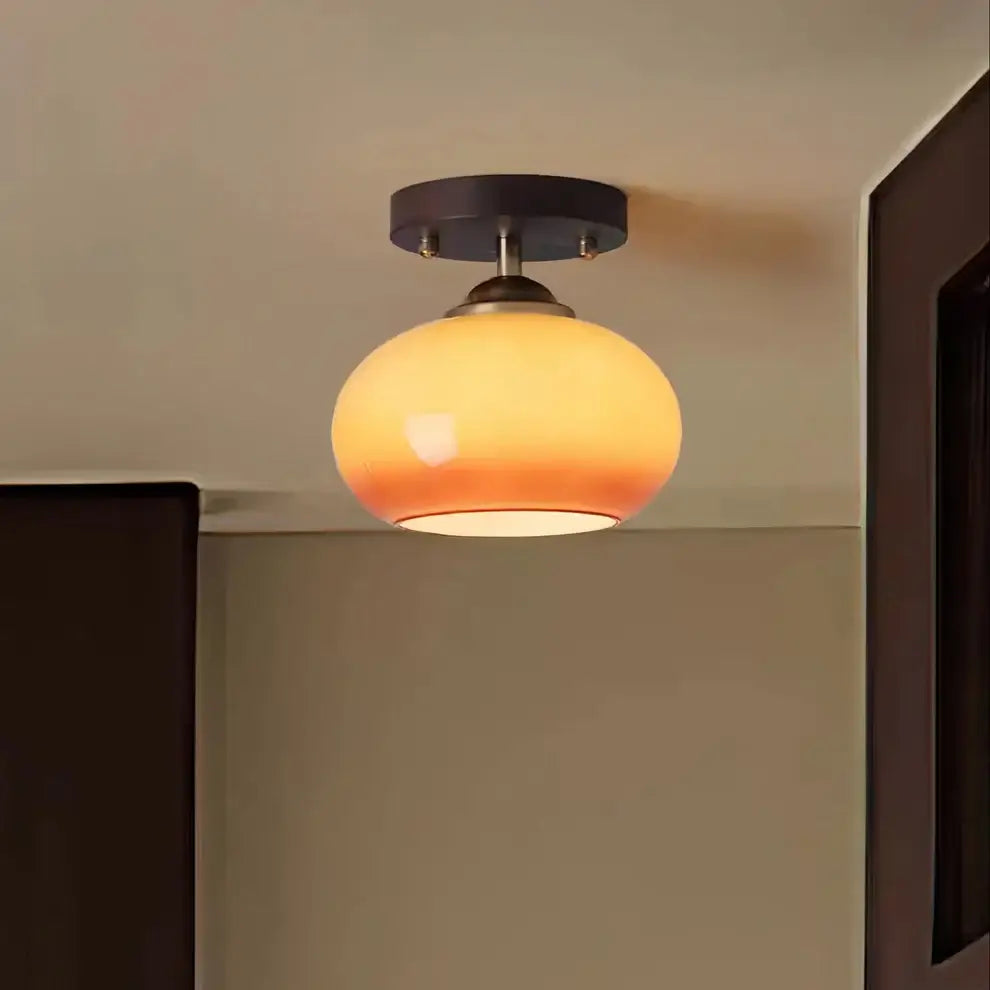 Close-up view of a modern walnut wood ceiling light featuring a spherical opal glass shade, highlighting craftsmanship.