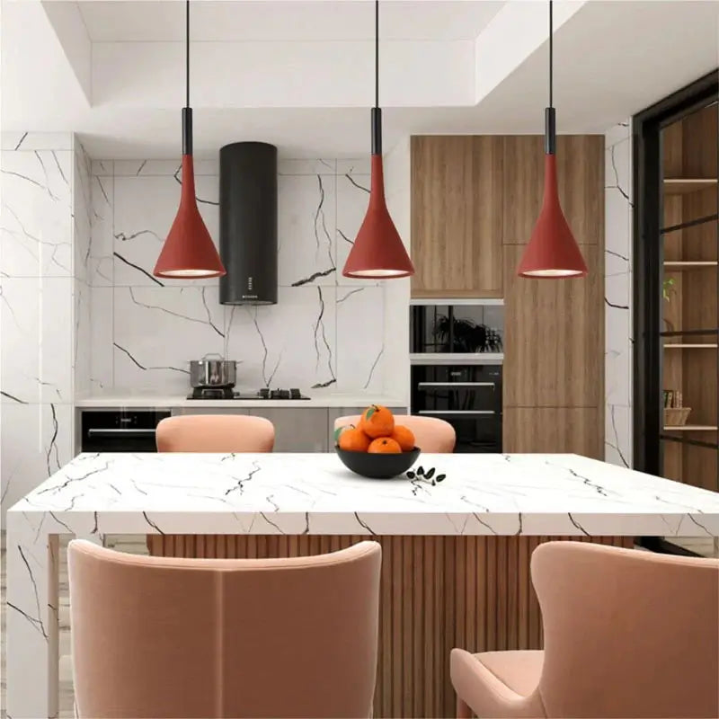 Three striking red modern pendant lights over a white marble kitchen island in a stylish kitchen, adding a vibrant pop of colour to kitchen designs