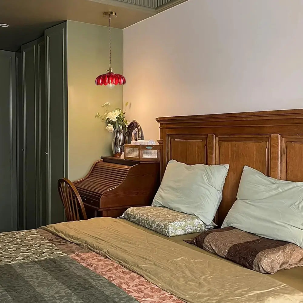 A red pendant light fixture hanging next to a bed, adding a vibrant and decorative touch to the bedroom.