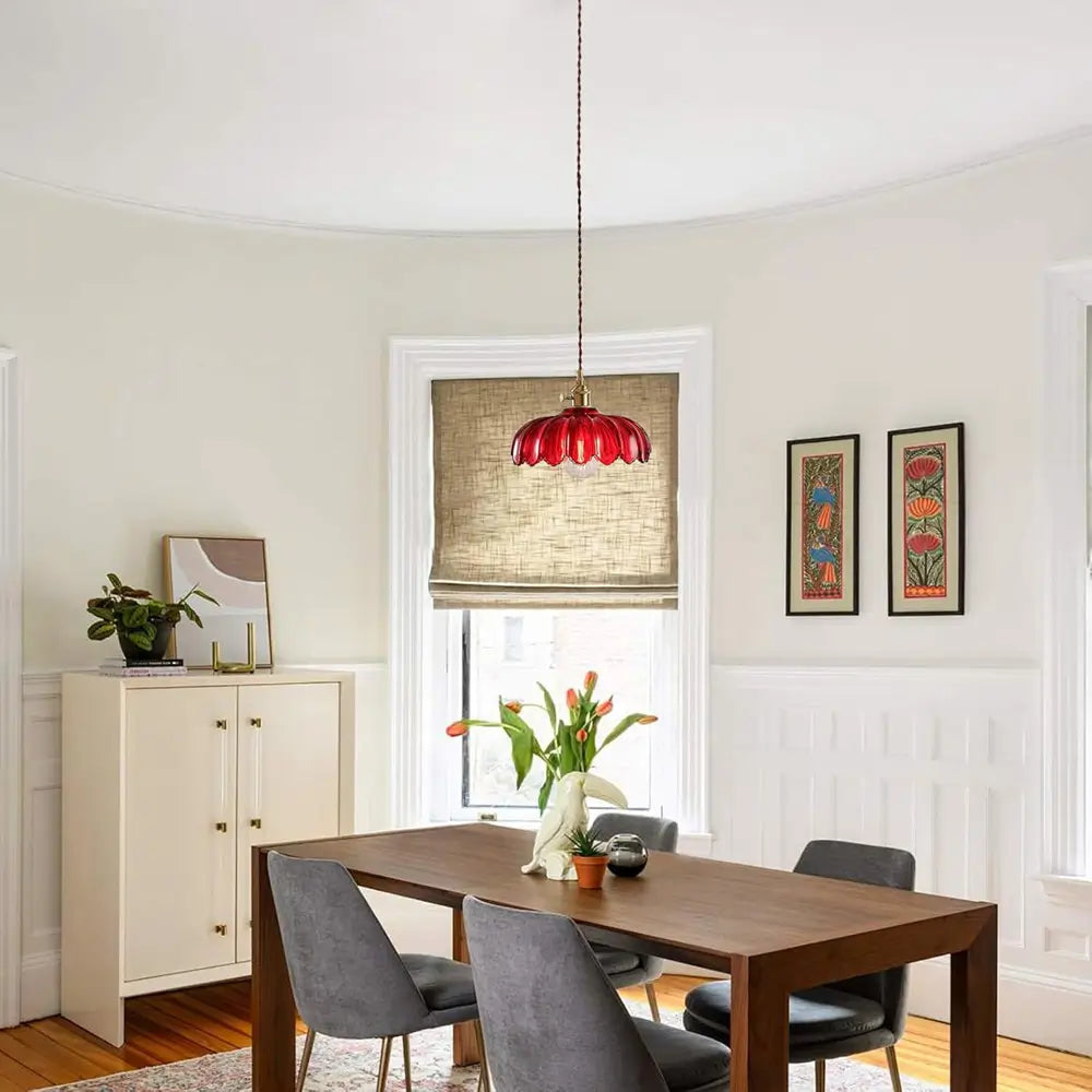 A red glass pendant light fixture providing stylish illumination over a dining table, perfect for modern dining room decor.