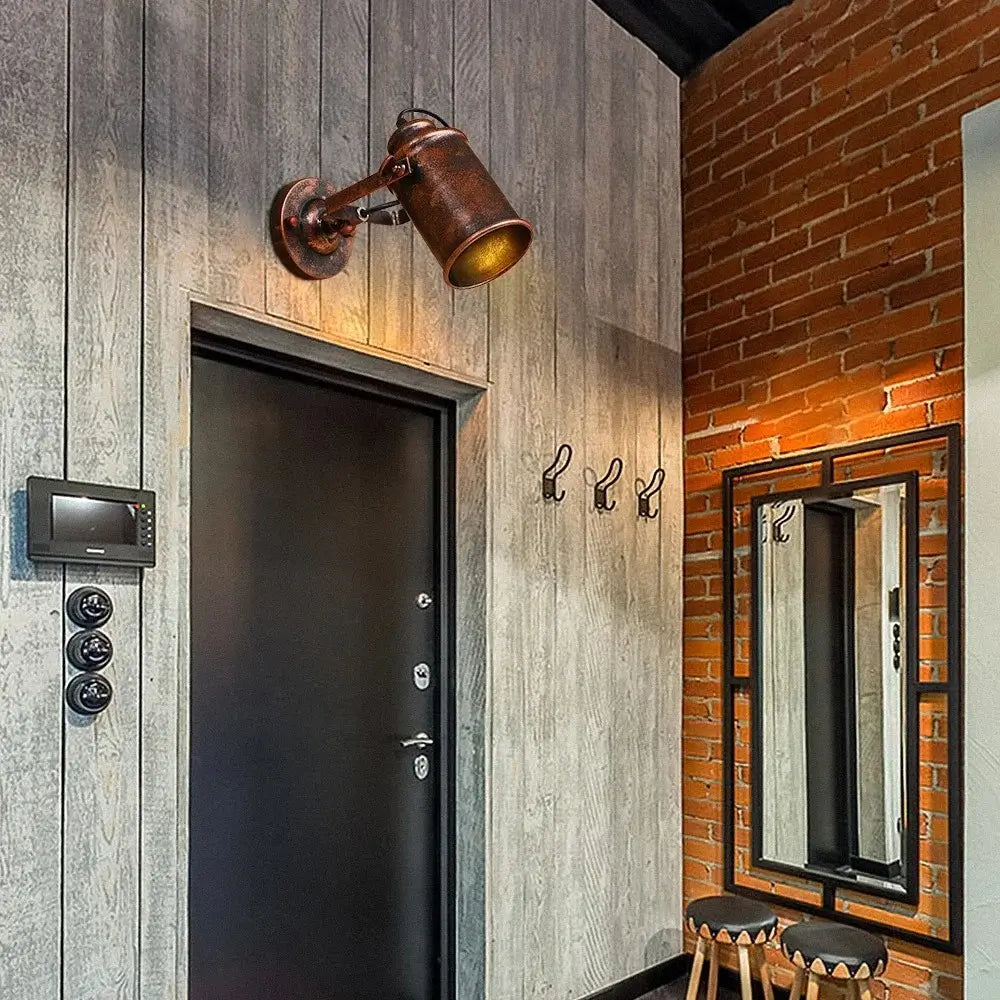 Rustic vintage wall sconce with an aged metal finish, mounted above a modern entryway door for a classic industrial look.