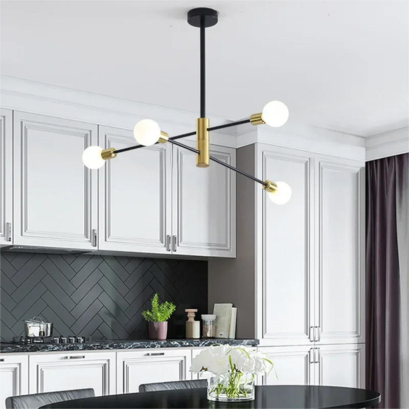 Elegant sputnik chandelier with a black and gold frame installed in a modern kitchen with white cabinets and a dark herringbone backsplash.