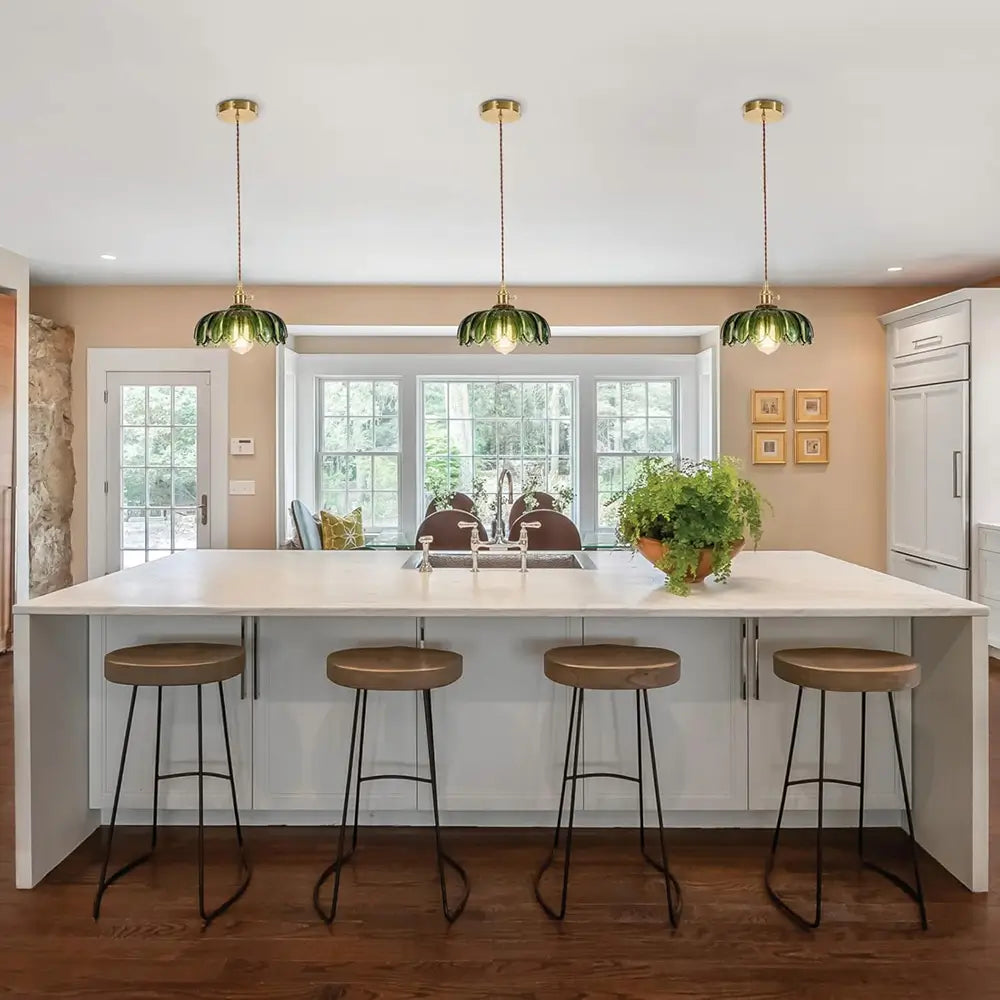 Two green pendant lights hang in a dining room with a large wooden table and chairs, creating a balanced lighting scheme.