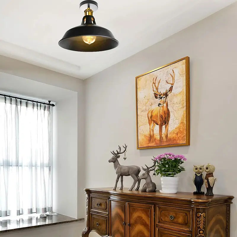Industrial black ceiling light used as part of a vintage-style room decor with artwork and wooden furniture.