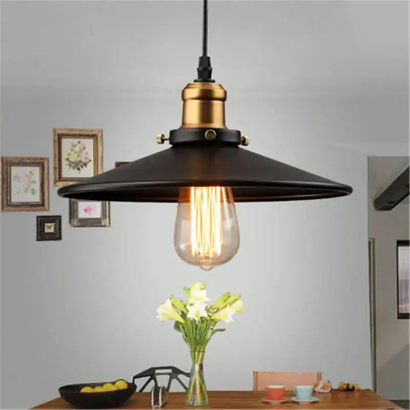 Single vintage black pendant light with gold accent and exposed Edison bulb, hanging over a kitchen or dining table.