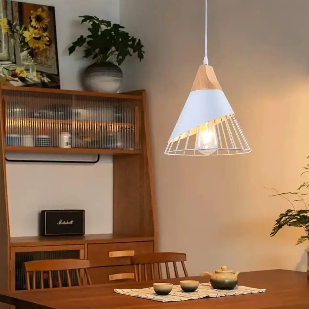 White and wood pendant light hanging in a cozy dining space with warm lighting and wooden furniture.