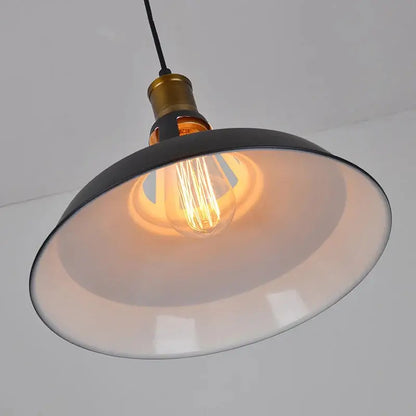 Close-up view of the matte black dome shade interior and vintage-style Edison bulb inside the industrial pendant light, highlighting the warm glow.