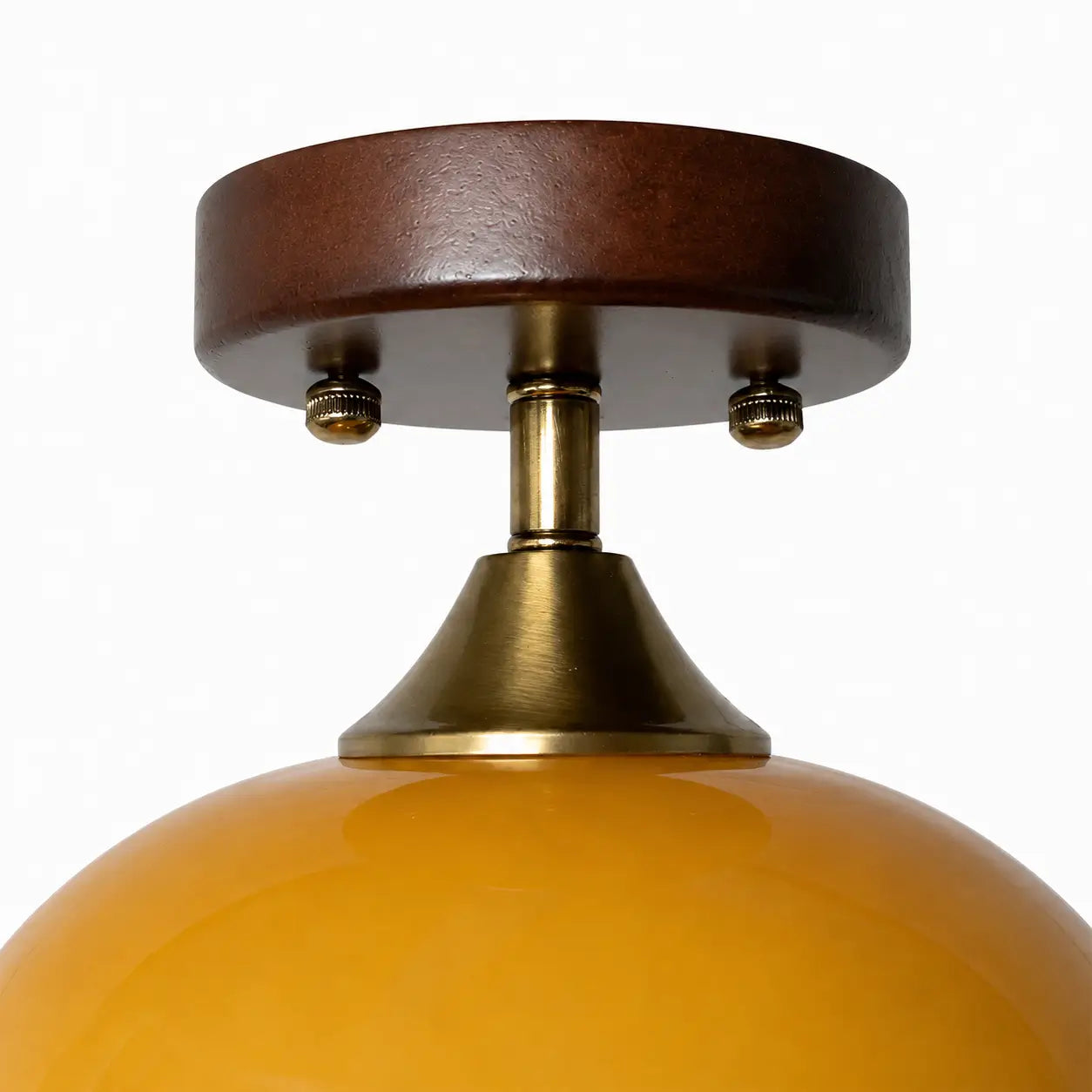Close-up of the walnut wood canopy and brass-toned neck above the amber glass shade