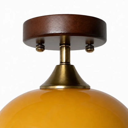 Close-up of the walnut wood canopy and brass-toned neck above the amber glass shade