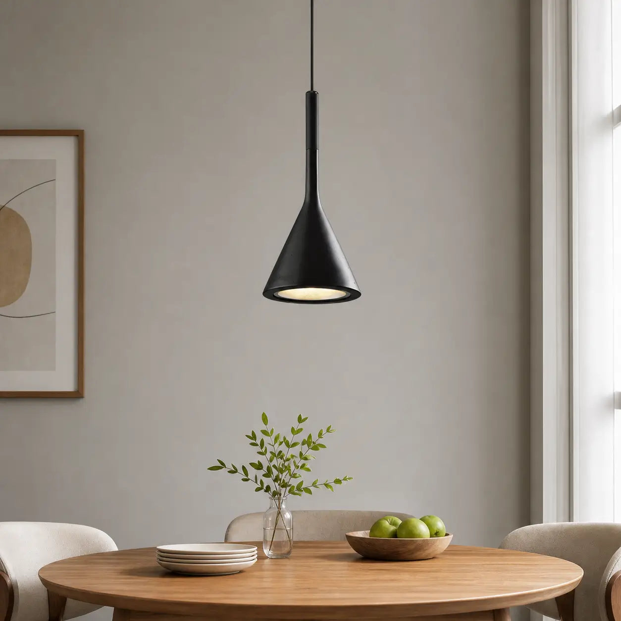 Single black cone pendant light centered above a round wood dining table near a large window.