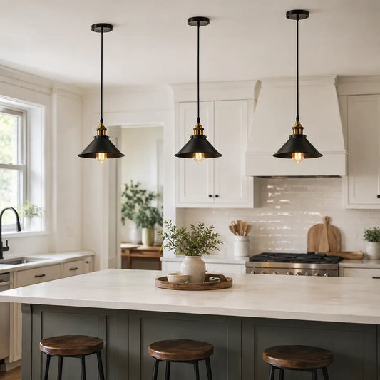 Three black cone pendant lights hanging above a bright kitchen island with white cabinets.