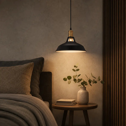 Matte black dome pendant light illuminating a bedside table in a warm neutral bedroom.
