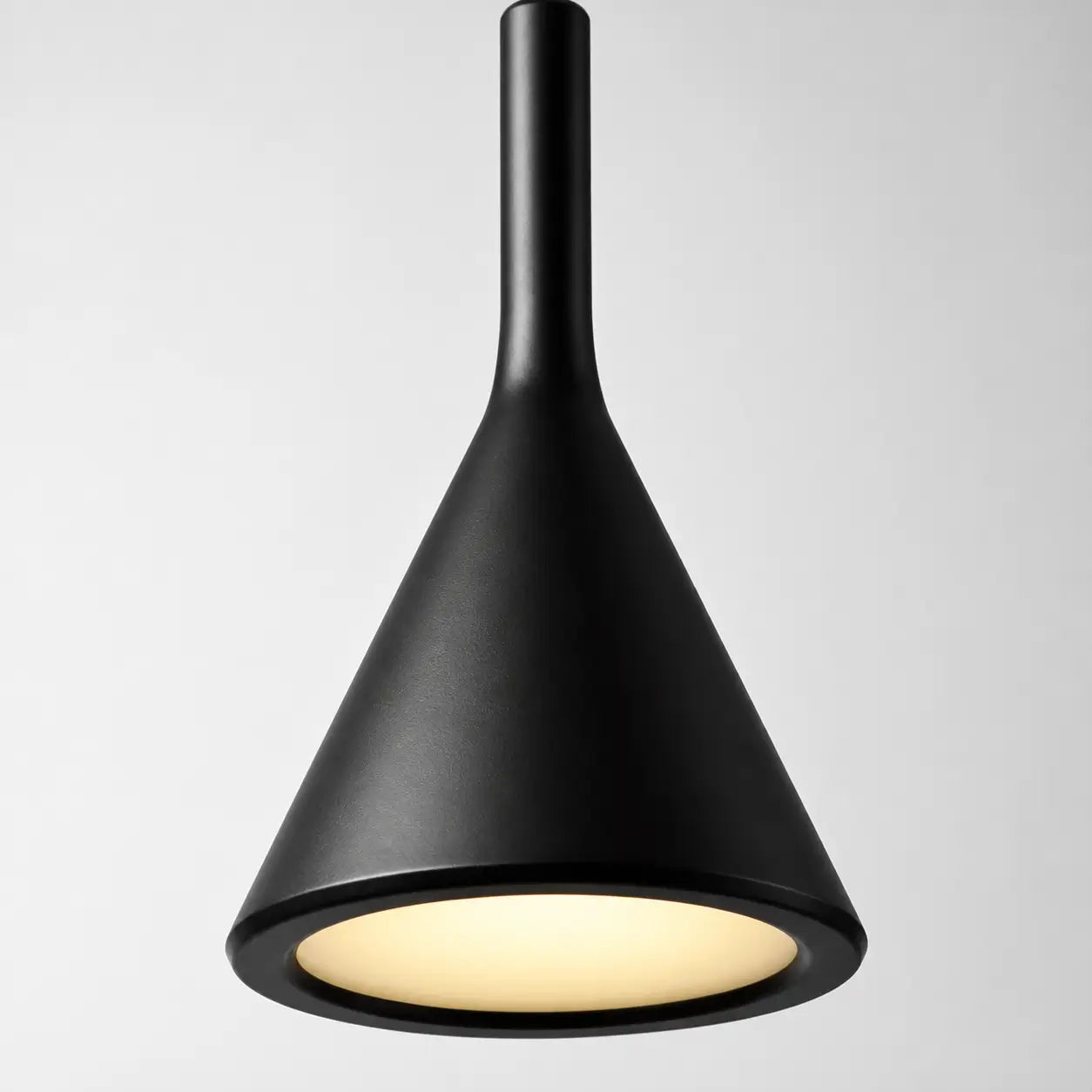 Close-up of the black metal cone shade with a softly illuminated recessed opening.