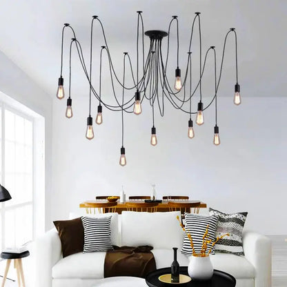 Black pendant lighting in a living room setting, showcasing a spider-style multi-bulb chandelier with long, draping black cables suspended above a white sofa and coffee table.
