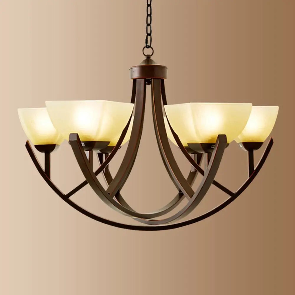 Bronze chandelier with six cream glass shades against a warm background.
