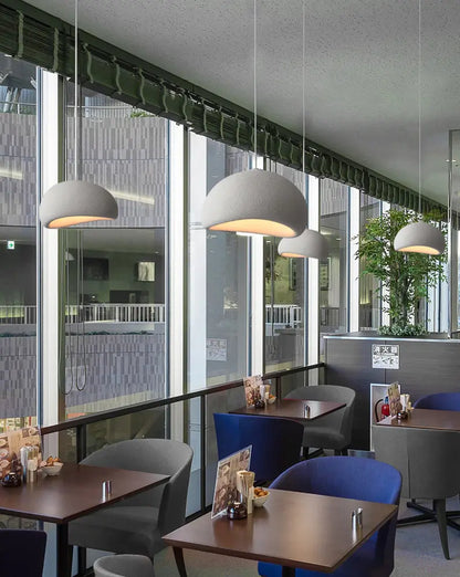 Pendant lighting in a modern cafe with natural tones and glass walls.