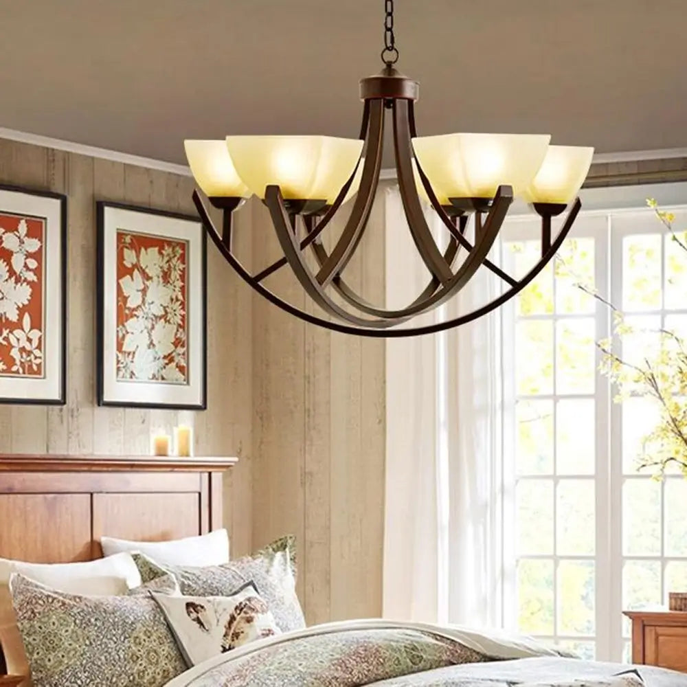 Luxury bronze chandelier installed in a cozy bedroom with wood decor.