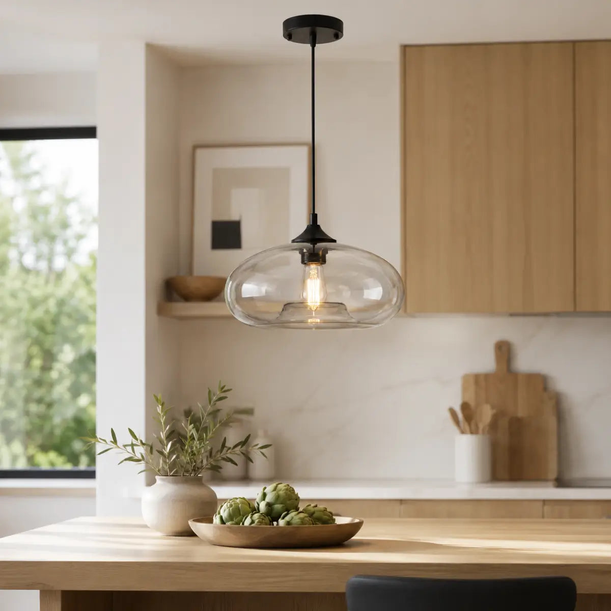 Clear oval glass pendant light installed above a wood kitchen island in a bright modern kitchen.