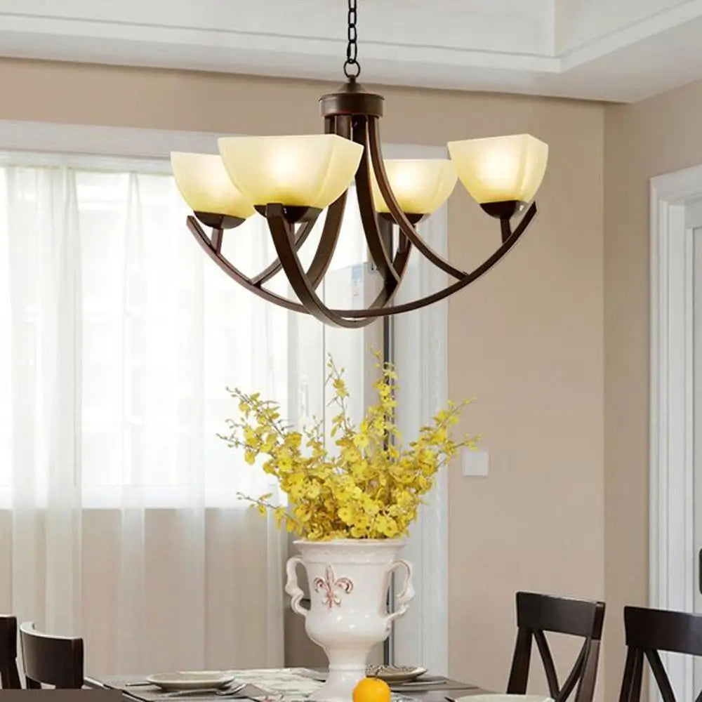 Bronze chandelier with cream glass shades hanging over a dining room table.
