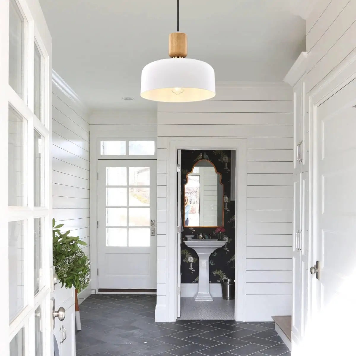 White pendant light hanging in a white hallway with farmhouse-style interior